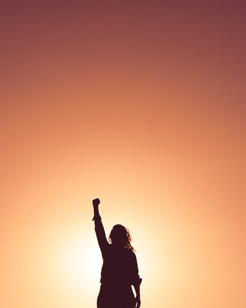 person in sunset raising her fist